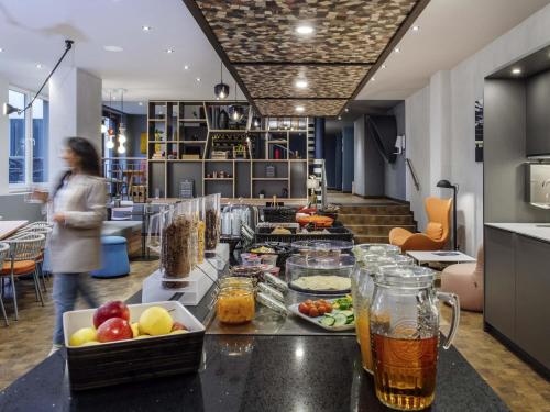 une femme debout dans une cuisine avec de la nourriture sur un comptoir dans l'établissement Aparthotel Adagio access Hamburg, à Hambourg