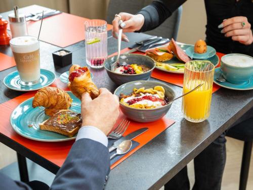 a table topped with plates of breakfast foods and drinks at ibis Styles Bielefeld City in Bielefeld