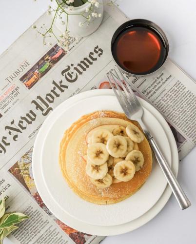 un piatto di pancake con banane e una tazza di caffè di Presidential One Bedroom Suite-Gold Crest Mall DHA Lahore Phase 4 a Lahore