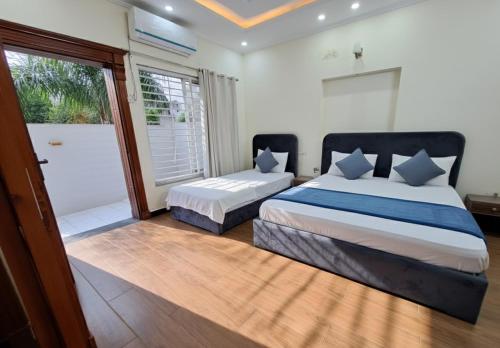 een slaapkamer met 2 bedden en een glazen schuifdeur bij Legacy Guest House in Islamabad