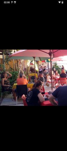 a group of people sitting at a table under an umbrella at Casa da Piscina in Maceió