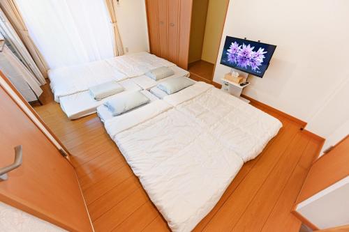 two beds in a small room with a tv at 民泊 Ichinomiya K Room 1A in Ichinomiya