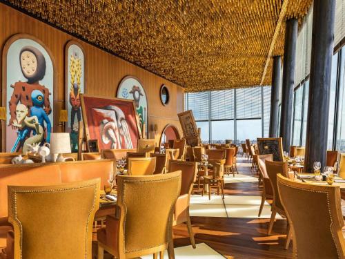 een eetkamer met stoelen, tafels en ramen bij Too Hotel & Spa Paris - MGallery Collection in Parijs