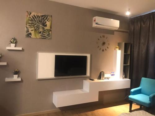 un soggiorno con una tv e una sedia blu di Mikayla Suite a Kota Bharu