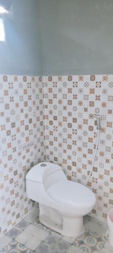 een badkamer met een toilet en een betegelde muur bij Uoemah gunung baturaden in Baturaden
