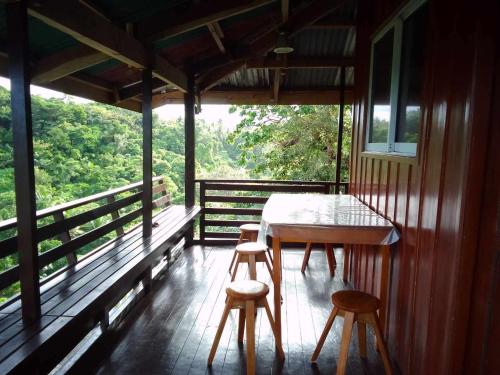 a table and two stools on the porch of a house at Hilltop Cottage in Cabulihan