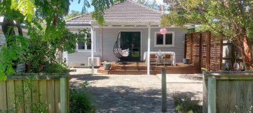 a white house with a porch with a swing at The River Bothy in Christchurch