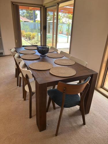 een houten tafel met stoelen en een kom erop bij Echucas Pawfect Accommodation - Dog Friendly in Echuca