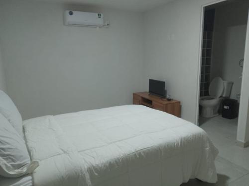 een slaapkamer met een wit bed en een televisie bij La Victoria Resort & Spa 