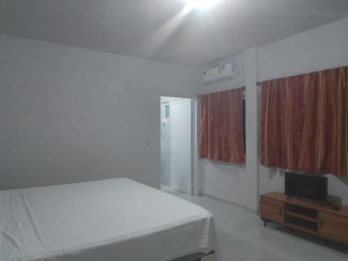 een witte slaapkamer met een bed en een televisie bij La Victoria Resort & Spa 