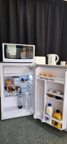Elle comprend un réfrigérateur blanc avec une porte ouverte et un four micro-ondes. dans l'établissement Avocado Orchard Retreat!, à Katikati