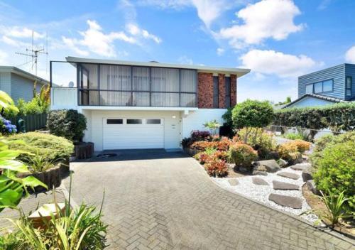 a house with a white garage and a driveway at Relaxed Mount Getaway Close to Beach & Town in Mount Maunganui