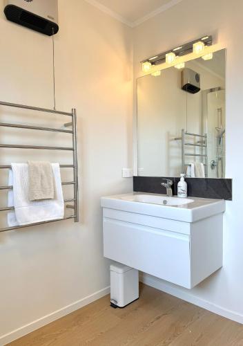 a bathroom with a white sink and a mirror at Relaxed Mount Getaway Close to Beach & Town in Mount Maunganui