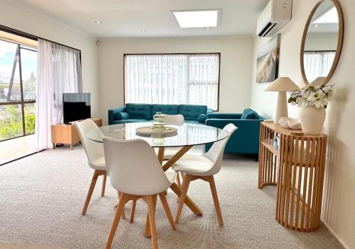 un soggiorno con tavolo in vetro e sedie bianche di Relaxed Mount Getaway Close to Beach & Town a Mount Maunganui