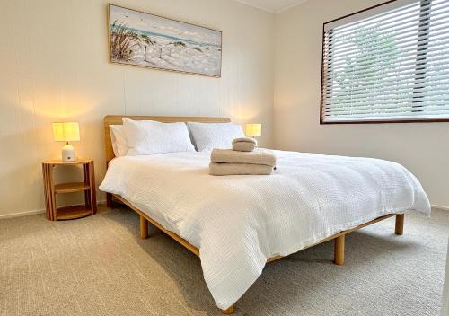 una camera da letto con un letto bianco con due lampade di Relaxed Mount Getaway Close to Beach & Town a Mount Maunganui