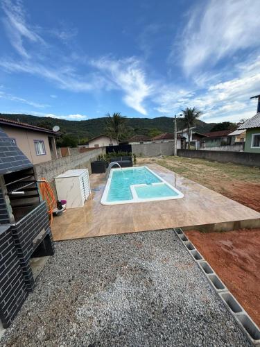 een zwembad in een tuin met een houten terras bij Casa Aconchego in Florianópolis