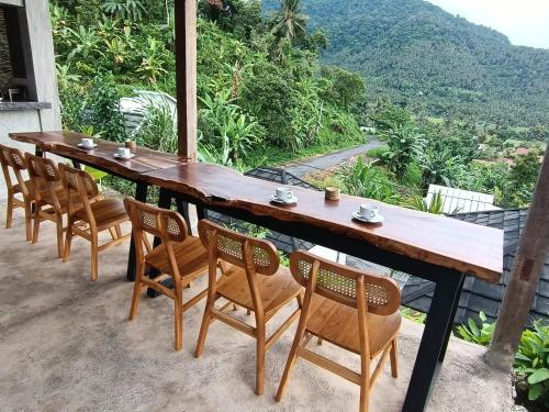 un tavolo e sedie in legno con vista sulle montagne di Sonnenhouse Lombok Kertaraharja a Luk