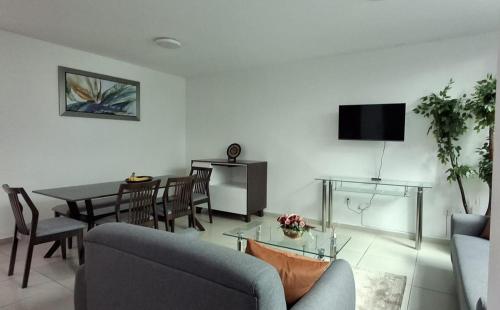 a living room with a table and chairs and a television at Cielito Lindo in Uruapan del Progreso