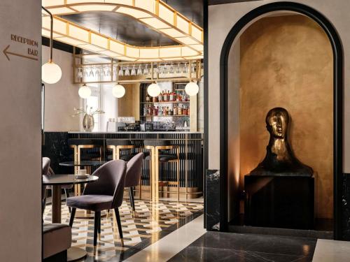 een restaurant met een bar met een standbeeld in het midden bij The Crown Krakow Center - Handwritten Collection ACCOR in Krakau