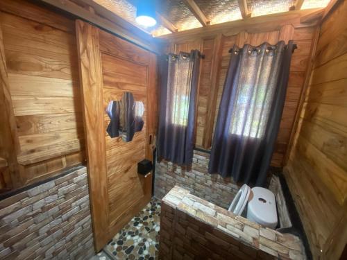 ein Badezimmer mit holzgetäfelten Wänden und einer Tür in der Unterkunft Batur Twin house in Kubupenlokan