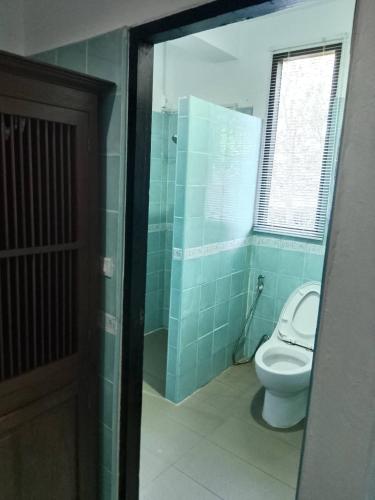 a bathroom with a toilet and green tile walls at Montana Home in Ban Pok Nai