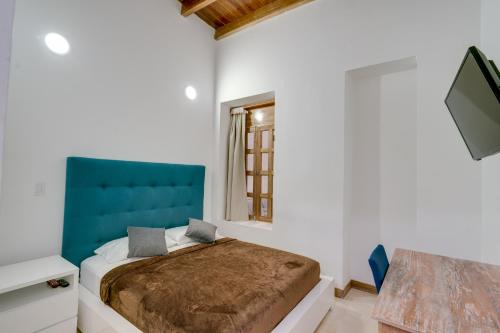 - une chambre avec un lit doté d'une tête de lit bleue et d'une télévision dans l'établissement Hotel Cattaleya, à Cali