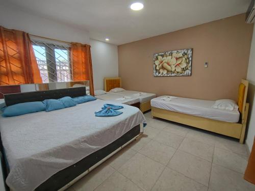 een slaapkamer met twee bedden en een schilderij aan de muur bij Hotel Kelly Mar in Tolú