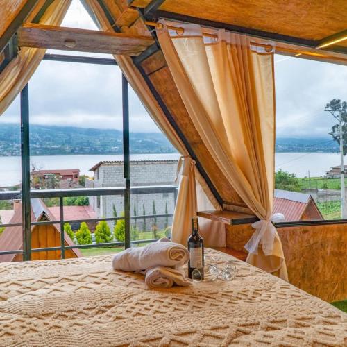 a bedroom with a bed with a bottle of wine and a window at Hospedaje Campo Lago y Glamping in Otavalo