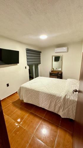 een slaapkamer met een wit bed en een houten vloer bij Hogar Kada in Tepic