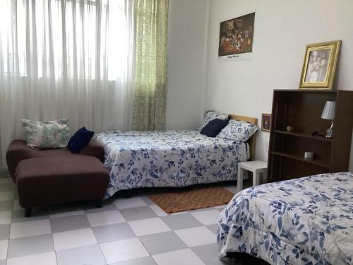 a bedroom with two beds and a chair and a window at Entire accommodation Departamento Mi Mexico in Mexico City