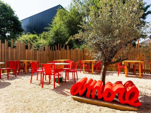 a bunch of red chairs and tables and a tree at Greet Hotel Limoges Nord in Limoges