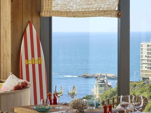 a table with a view of the ocean from a window at Le Talaia Hôtel & Spa Biarritz - MGallery Collection in Biarritz