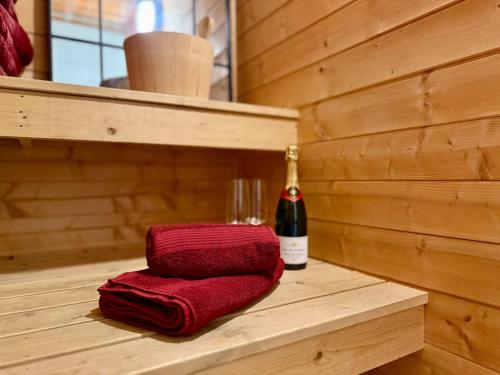a red towel sitting on a wooden shelf with a bottle of wine at Unique view! Modern apartment with sauna in Vossevangen