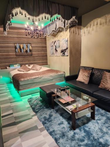 een slaapkamer met een bed, een bank en een tafel bij ホテルメイプル in Odate