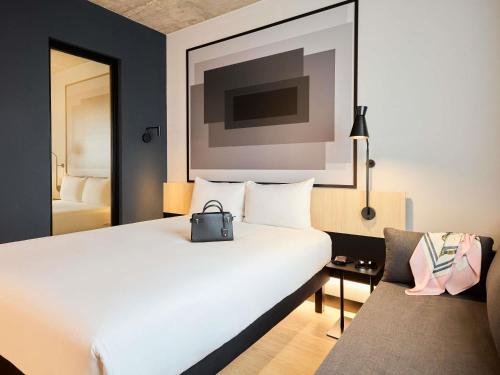een hotelkamer met een wit bed en een stoel bij ibis Madrid Norte Las Tablas in Madrid