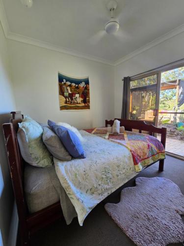 ein Schlafzimmer mit einem Bett und einem Gemälde an der Wand in der Unterkunft Gold Coast Hinterland Experience No ppl 8 in Tallebudgera