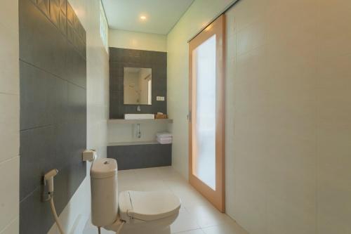 ein Badezimmer mit Toilette, Waschbecken und Spiegel in der Unterkunft Govardhan Nusa Penida in Nusa Penida