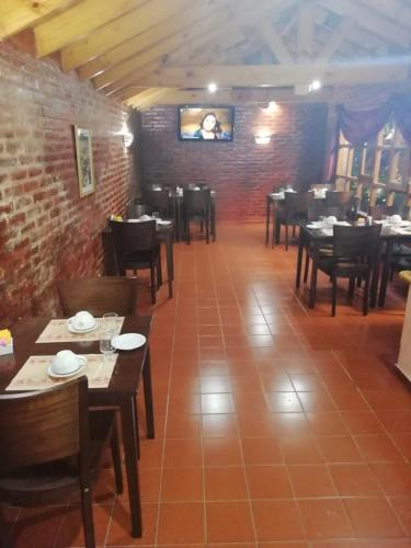 a dining room with tables and chairs and a brick wall at Hotel Lincoln in Villa Gesell