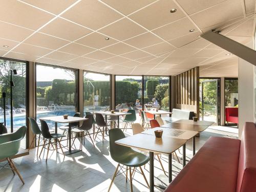 een restaurant met tafels en stoelen en een zwembad bij ibis Avignon Sud in Avignon