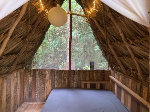 ein Zimmer in einer Holzhütte mit einem großen Fenster in der Unterkunft Serene and peaceful farmstay near Xaibe in Corozal