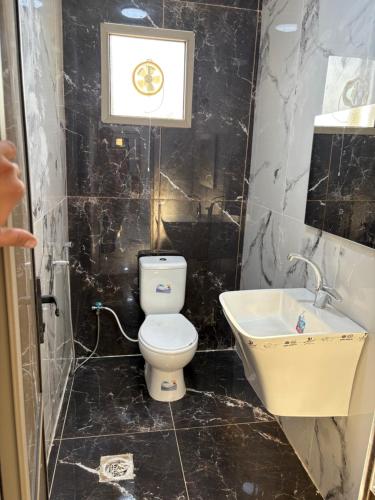 a black tiled bathroom with a toilet and a sink at Golden Stay in Jerash