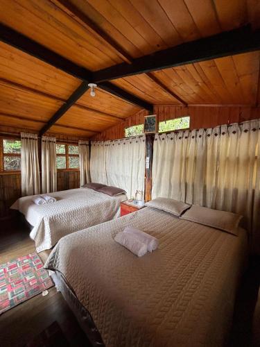 a bedroom with two beds in a wooden house at Entre Rocas y Cristales in Ráquira