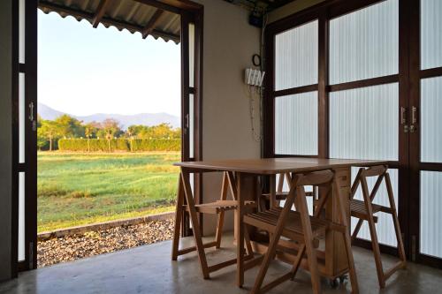 einen Holztisch und Stühle in einem Zimmer mit Fenster in der Unterkunft Rimtai Hütte in Mae Rim