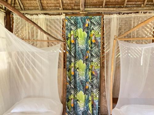 a room with two beds and a curtain with trees at Backpacker's Hill Resort in San Vicente