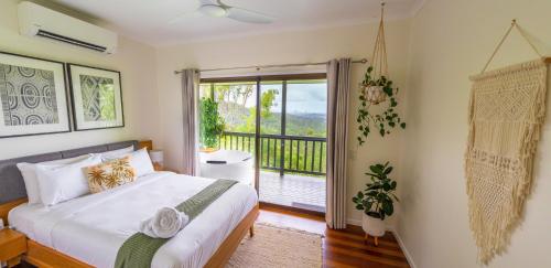 a bedroom with a large bed and a balcony at Nebesa Tree top villas in Mudgeeraba
