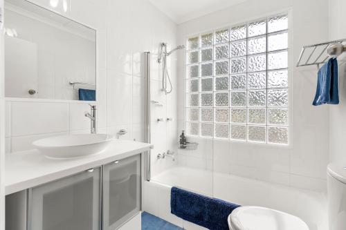 een witte badkamer met een wastafel en een douche bij Tide & Timber - Adventure Bay in Adventure Bay