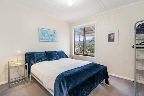 een slaapkamer met een bed met blauwe lakens en een raam bij Tide & Timber - Adventure Bay in Adventure Bay