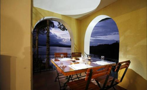een eetkamer met een tafel en twee gebogen ramen bij Vista Del Lago in Ambalavayal