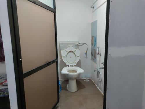 een badkamer met toilet met deksel bij Bageshree homestay in Guhagar
