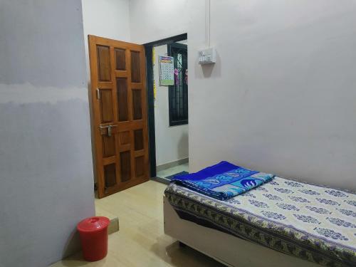 een kleine kamer met een bed en een deur bij Bageshree homestay in Guhagar